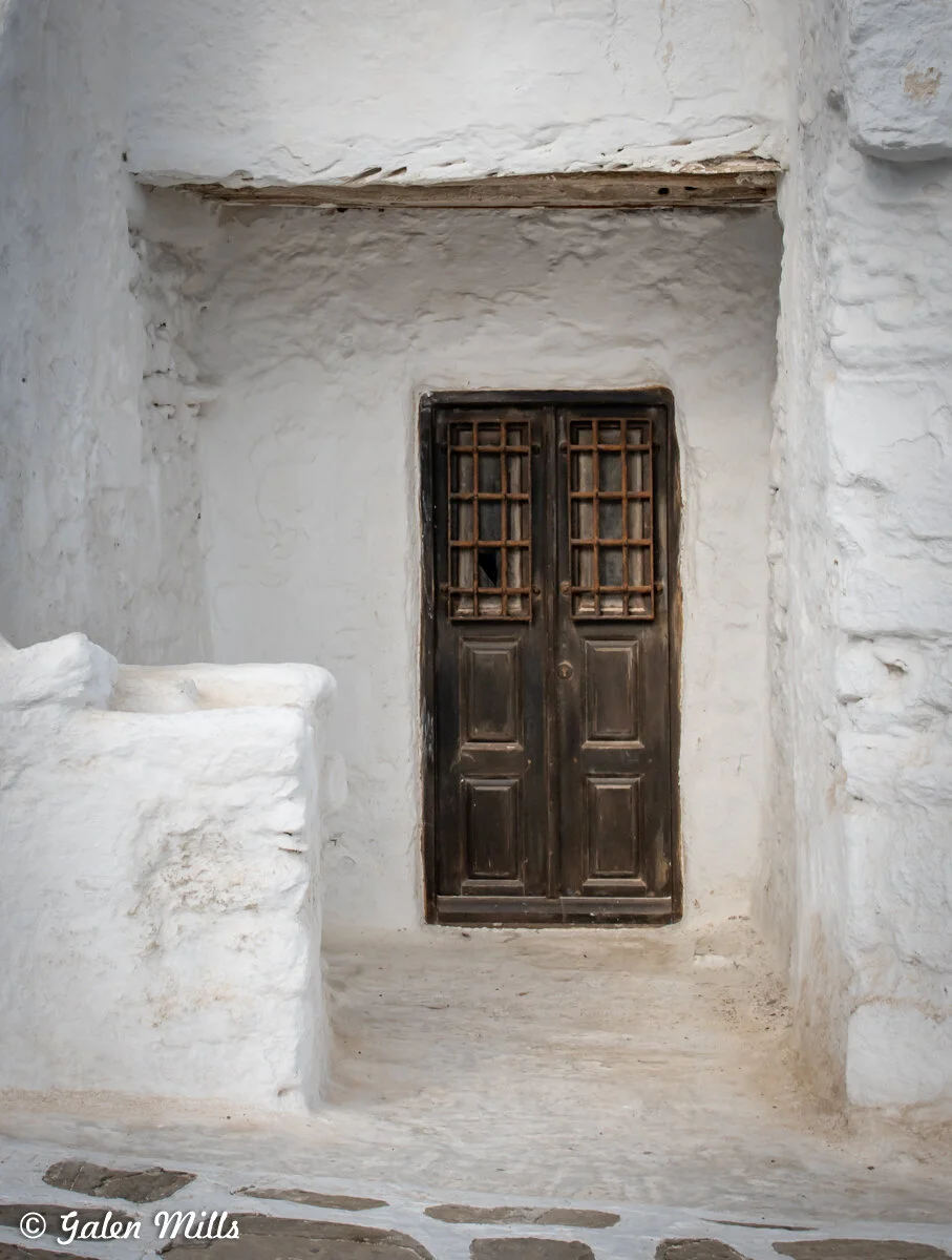 A rustic wooden door set in a whitewashed stone wall.