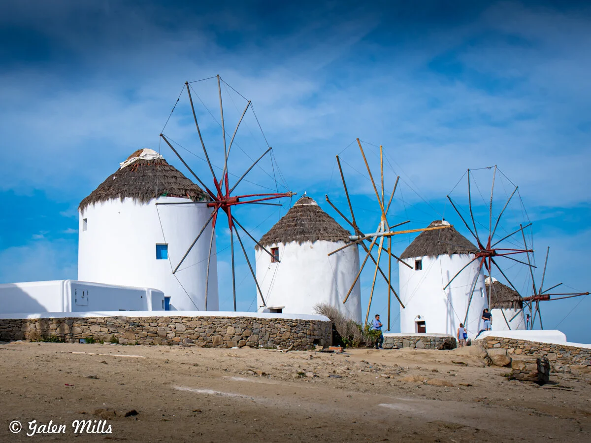 Traditional windmills on Mykonos, Greece against a blue sky.