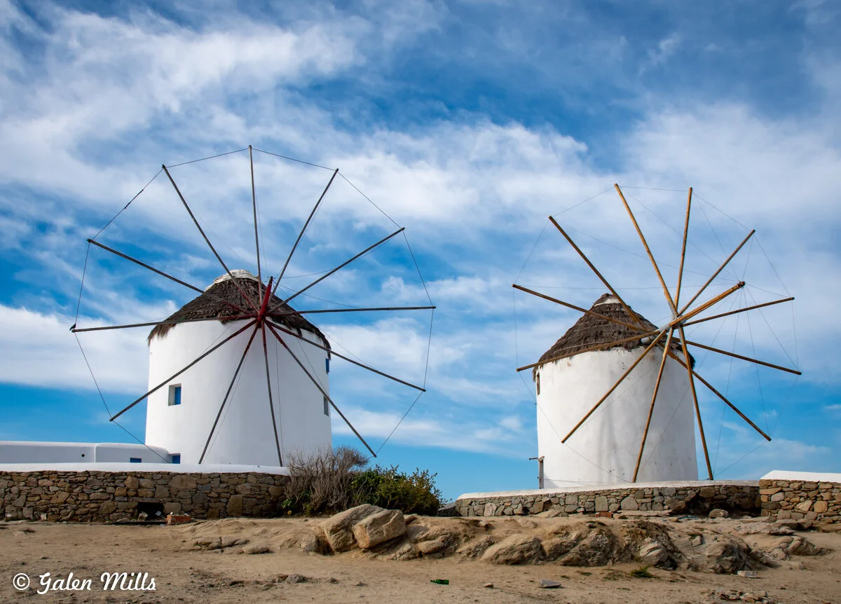 Windmills in Mykonos, Greece against a blue sky.