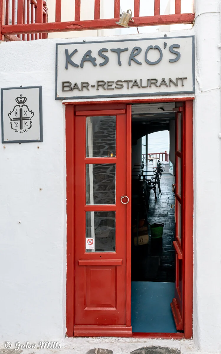 Entrance of Kastro's bar-restaurant featuring a red door and sign.
