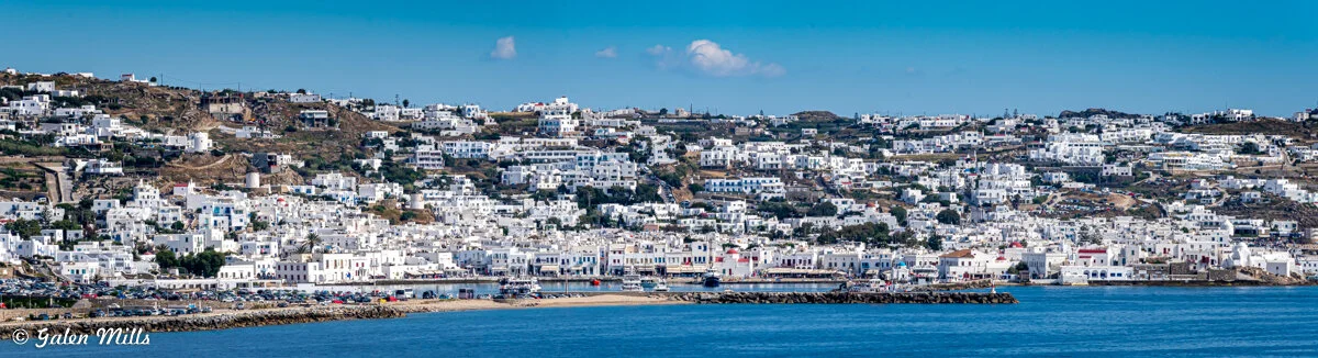 Panoramic view of a seaside town with white buildings on a hill.
