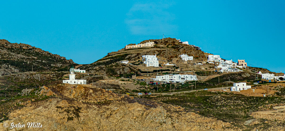 Scenic view of white buildings on a rugged hillside against a clear blue sky.