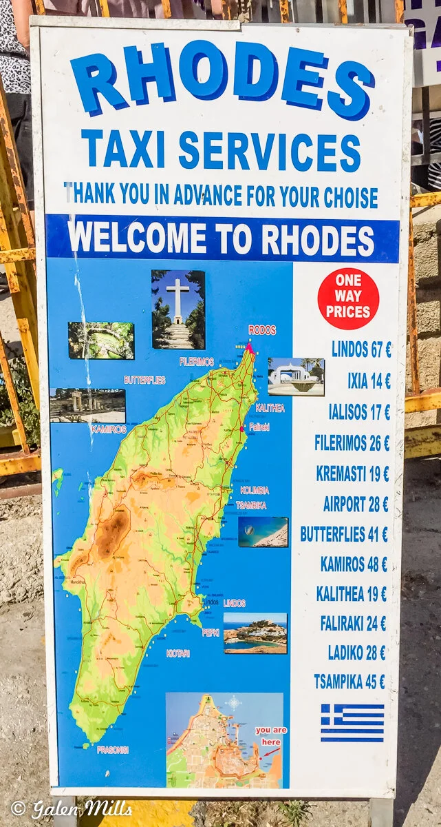 Sign for Rhodes taxi services with map and prices