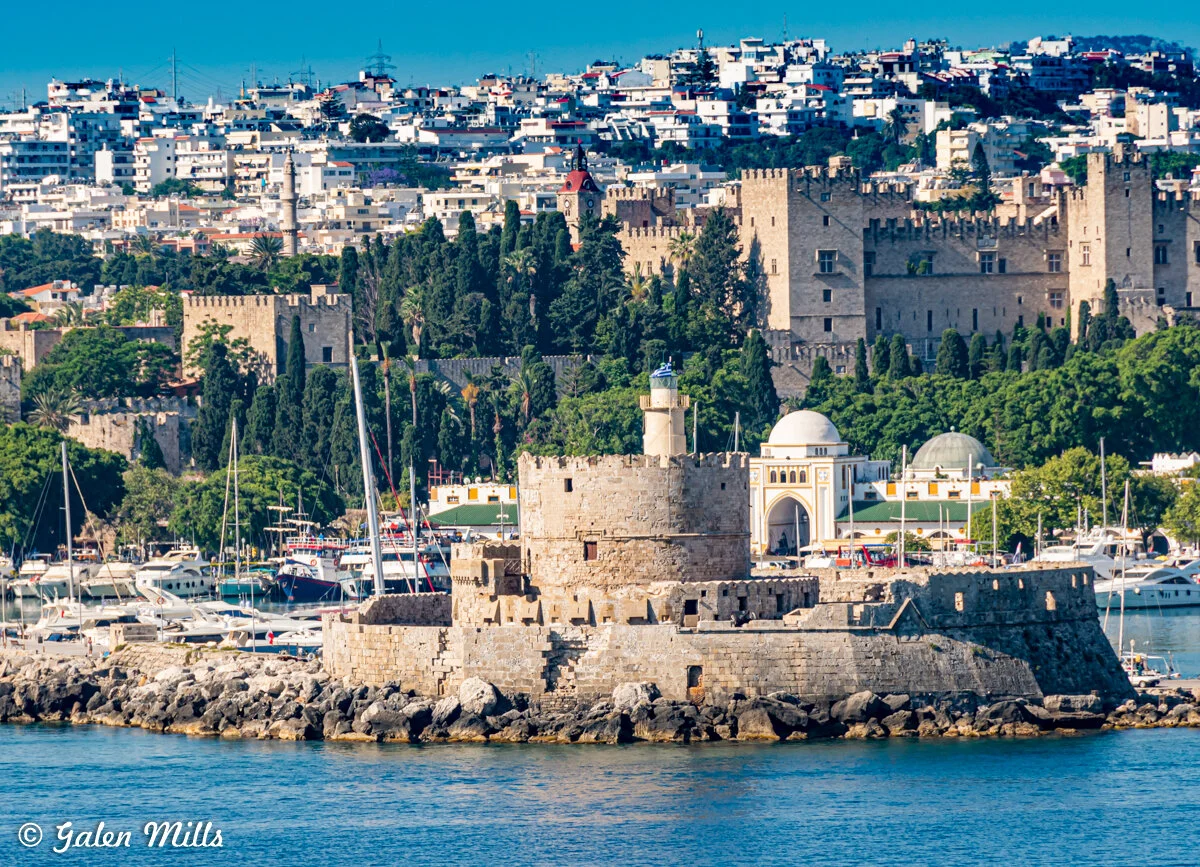 View of the medieval fortifications of Rhodes, Greece, with the Palace of the Grand Master and a marina with yachts in the foreground.