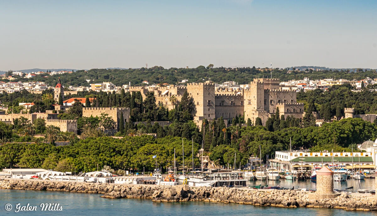 Medieval castle with lush greenery and boats in harbor