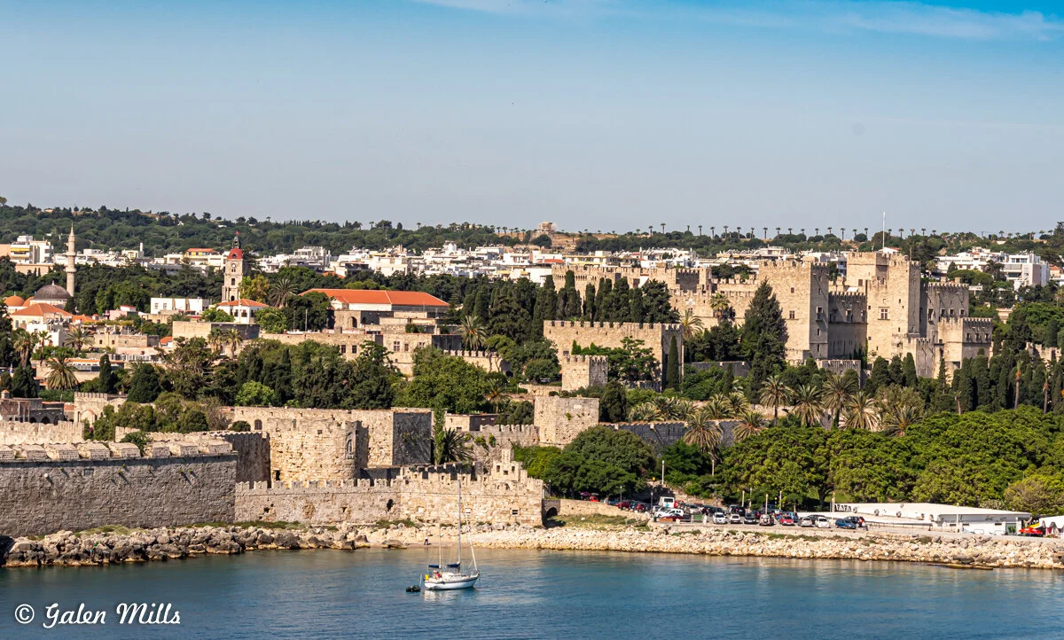 View of Rhodes, Greece with medieval castle, lush greenery, and waterfront