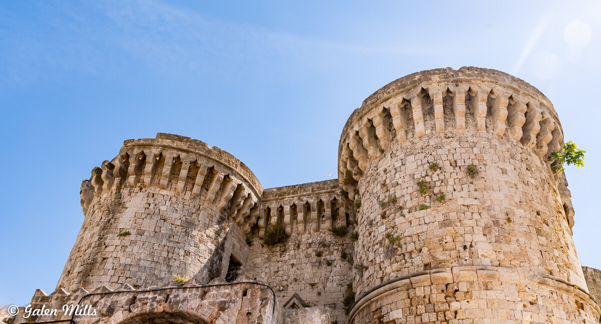 Ancient stone castle towers with battlements under a clear blue sky.