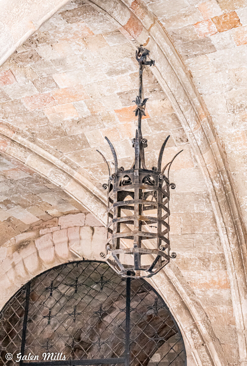 Gothic-style iron lantern hanging from an arched stone ceiling.
