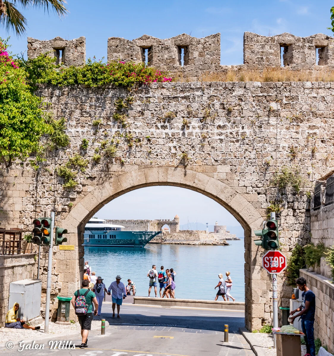 Stone archway with people walking and a cruise ship in the background