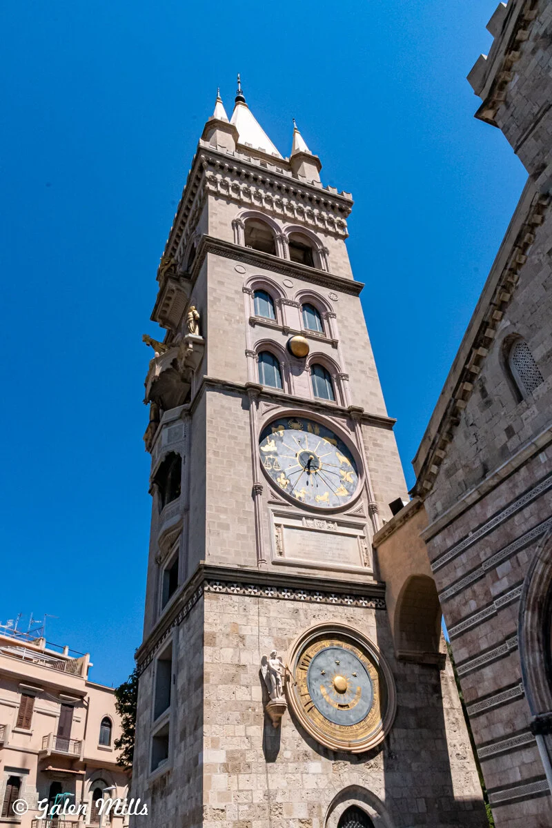 Clock tower with astronomical clock and statues against a clear blue sky