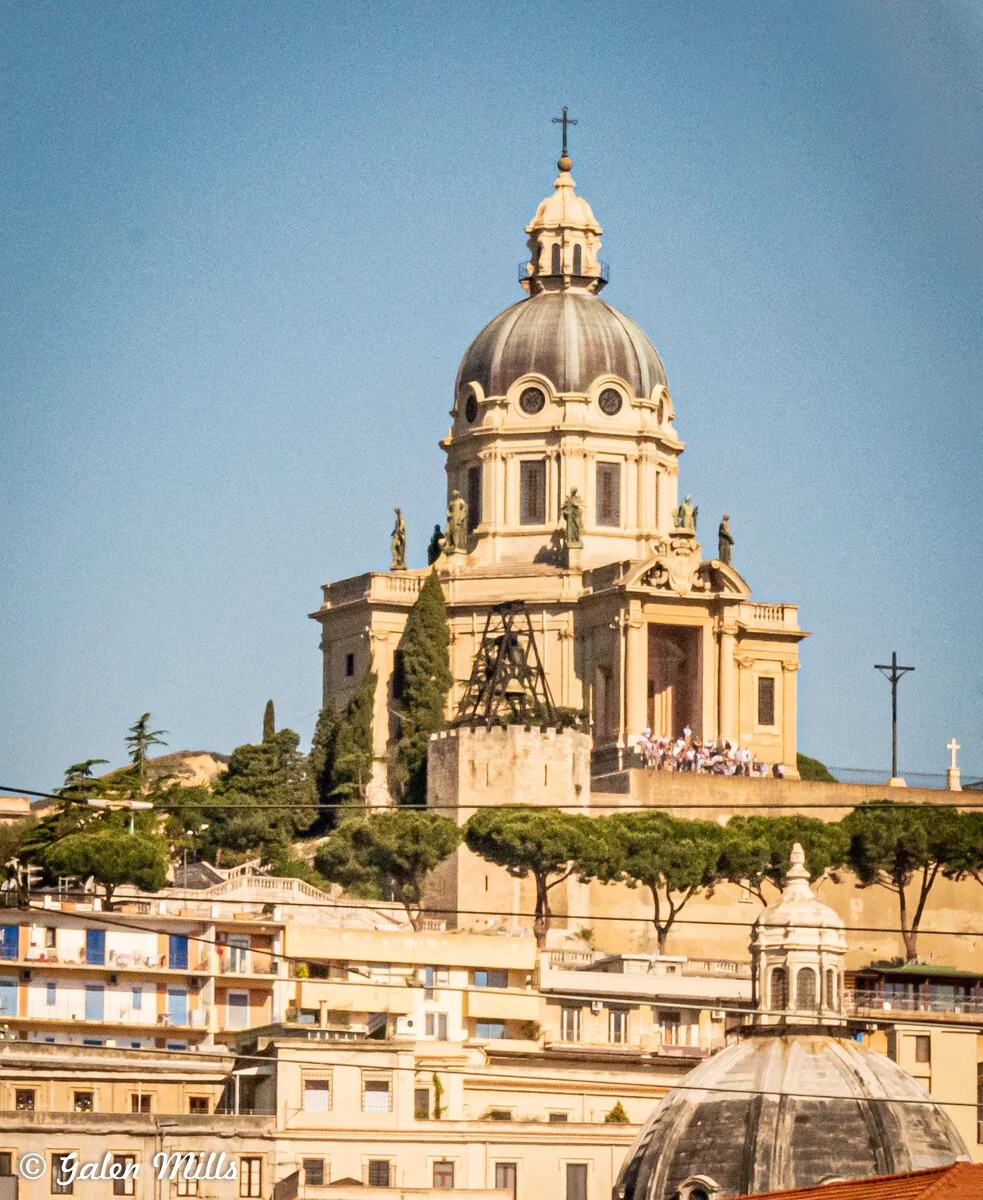 View of the Sanctuary of Christ the King in Messina, Italy, featuring the church dome and surrounding buildings.