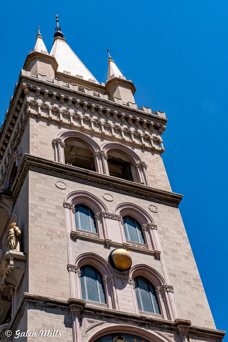 Close-up of a church tower with decorative architecture under a clear blue sky.