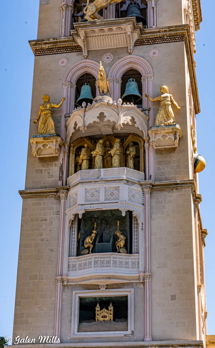 Detail of the Bell Tower of the Cathedral of Messina, featuring mechanical golden statues, architectural embellishments, and bells.