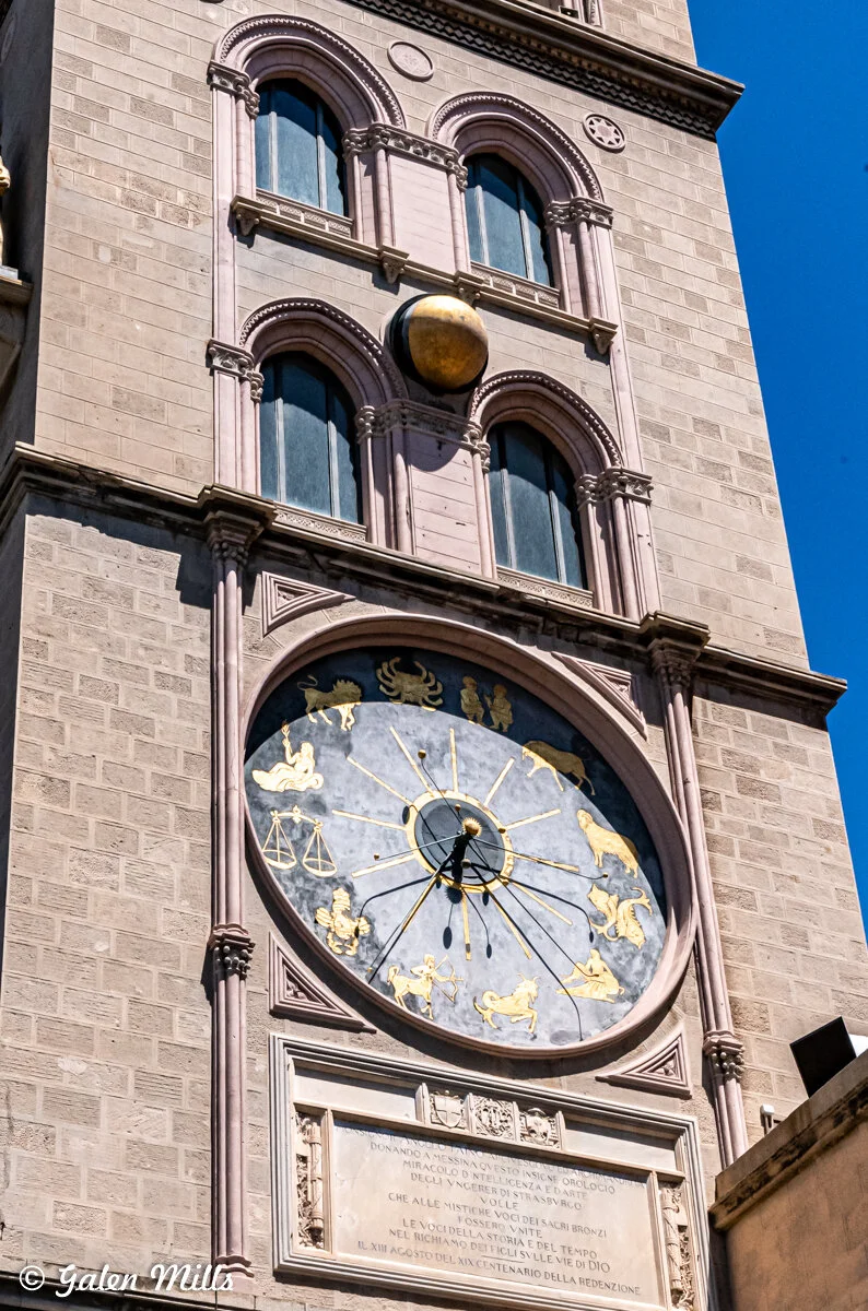 Architectural clock with zodiac signs on a historical building exterior.
