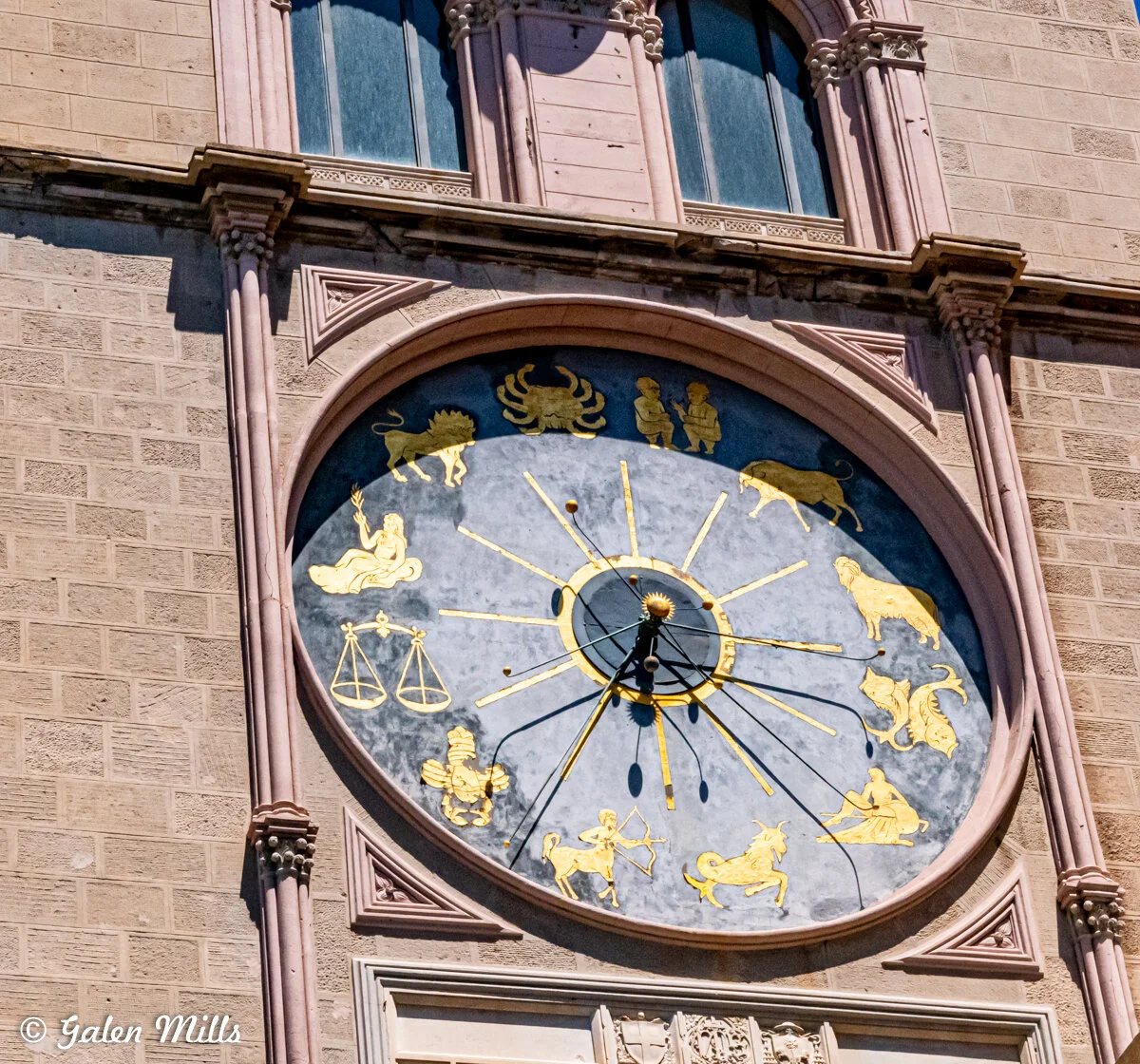 Close-up of an astronomical clock with zodiac signs in gold on a blue background.
