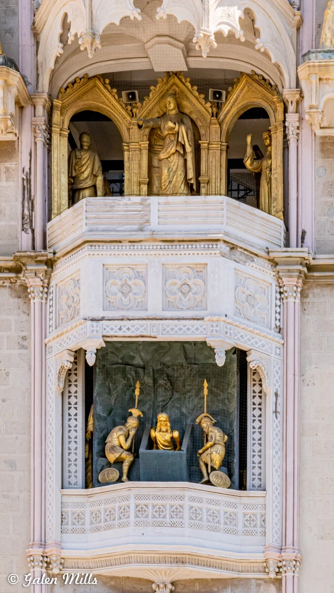 Detail of astronomical clock in Prague featuring religious figures in architectural setting.