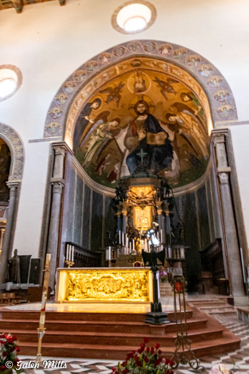 Church altar with religious fresco, ornate decorations, and candles