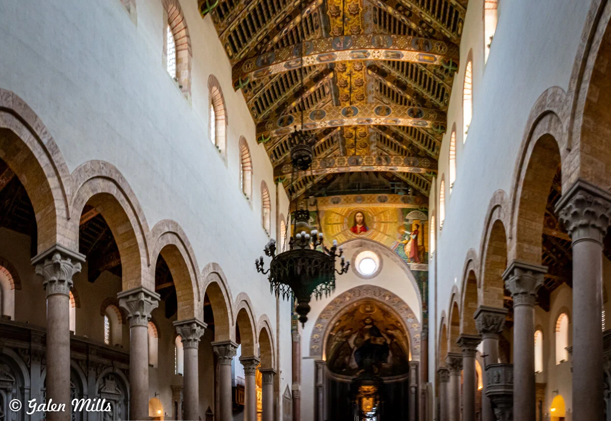 Interior of a historical church with ornate ceiling, arches, and columns.