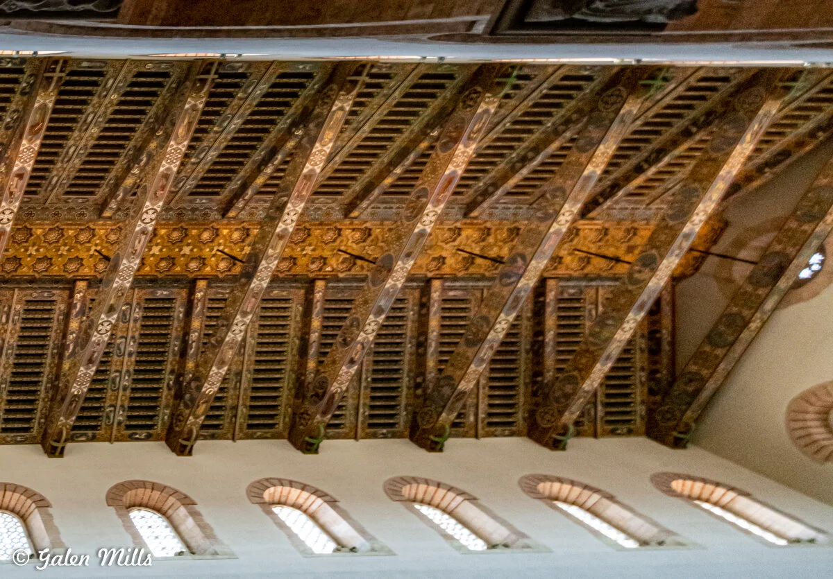 Ornate wooden ceiling with intricate carvings and patterns inside a historic building.
