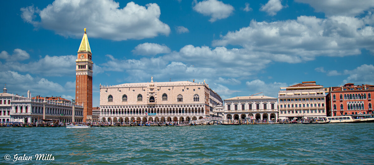Venice skyline featuring St. Mark's Campanile and Doge's Palace with a canal in the foreground.
