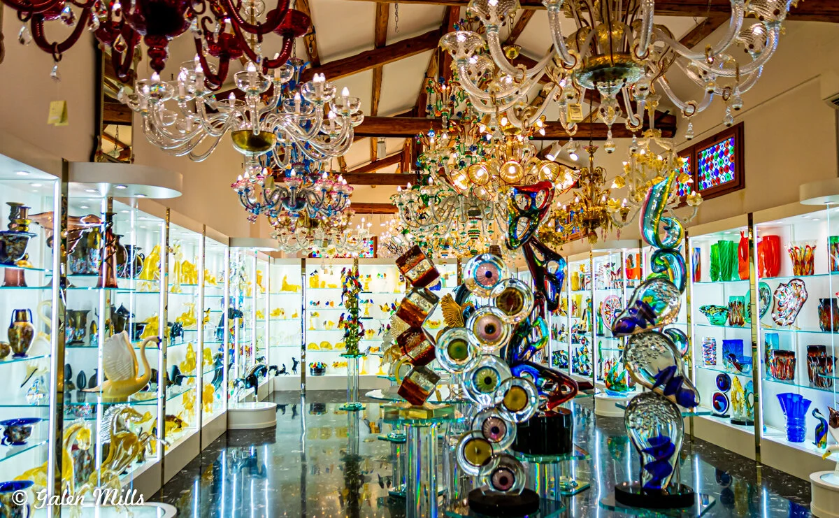 Colorful glass art pieces and chandeliers on display in a gallery.