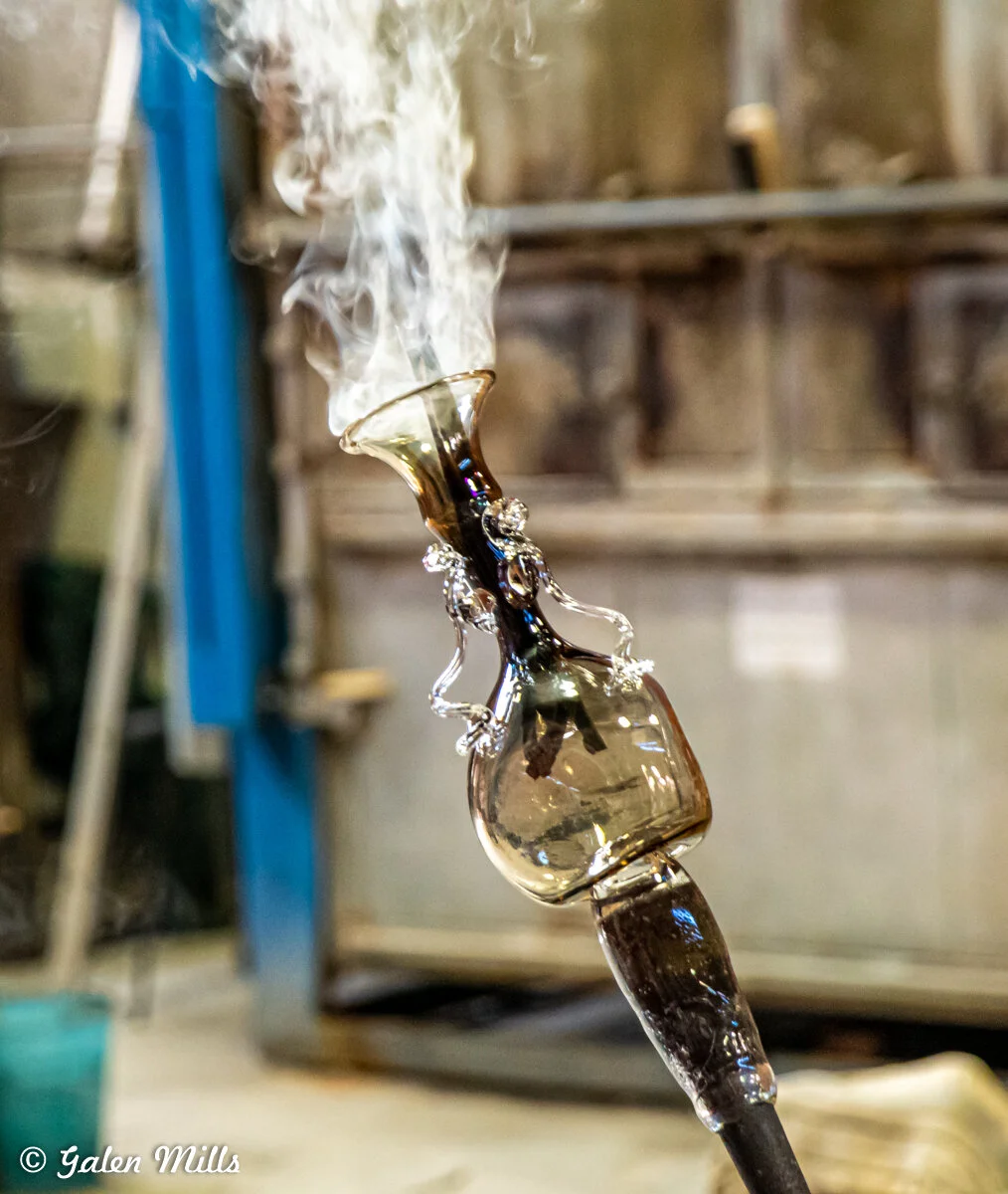 Glassblowing process with smoke rising from hot glass