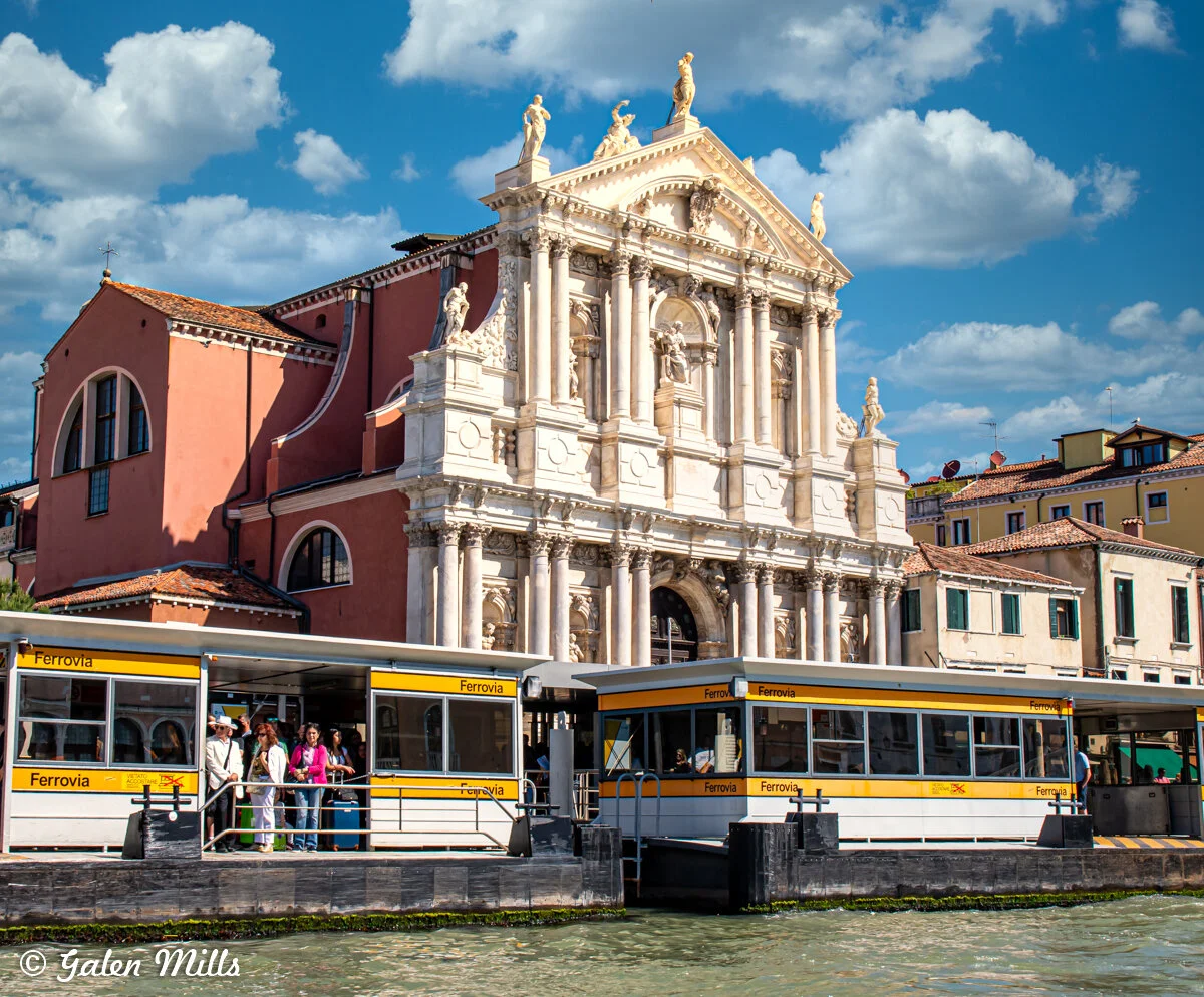 Vaporetto stop near Santa Lucia Train Station in Venice, Italy with baroque architecture and tourists.