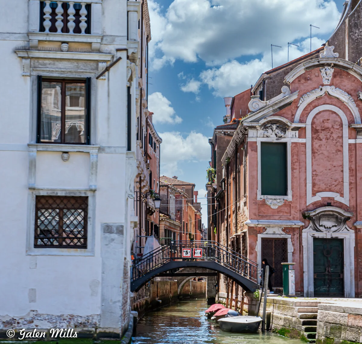 Venetian canal with a bridge and historic buildings on a sunny day.