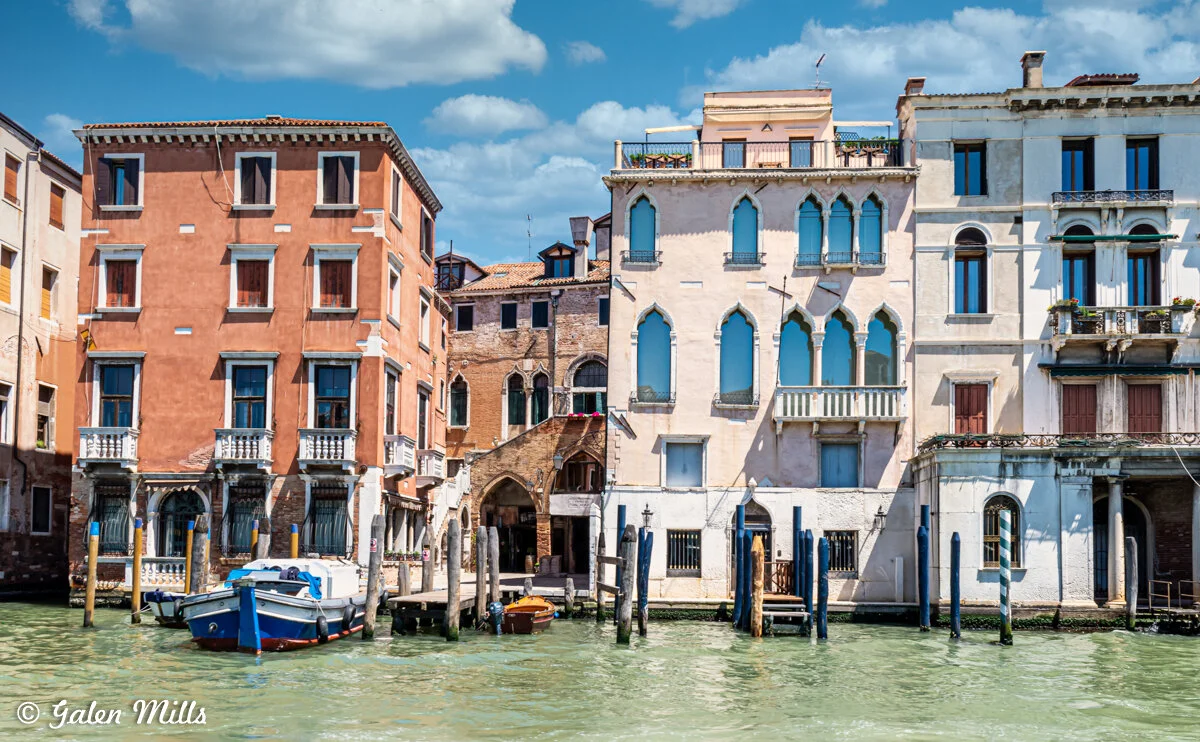 Colorful Venetian buildings along a canal with boats moored in Venice, Italy.