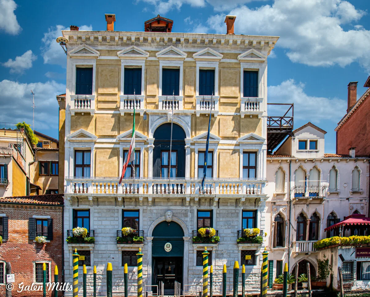Historic building with Italian flag, waterfront, sunny day.
