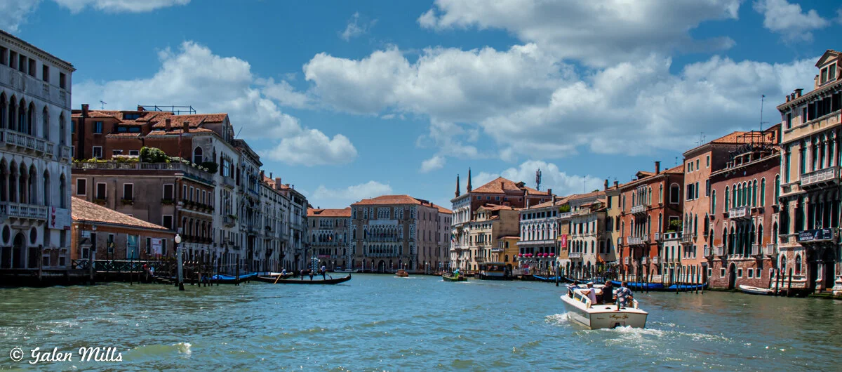 View of a canal in Venice with historic buildings lining the waterway and a boat in the foreground.