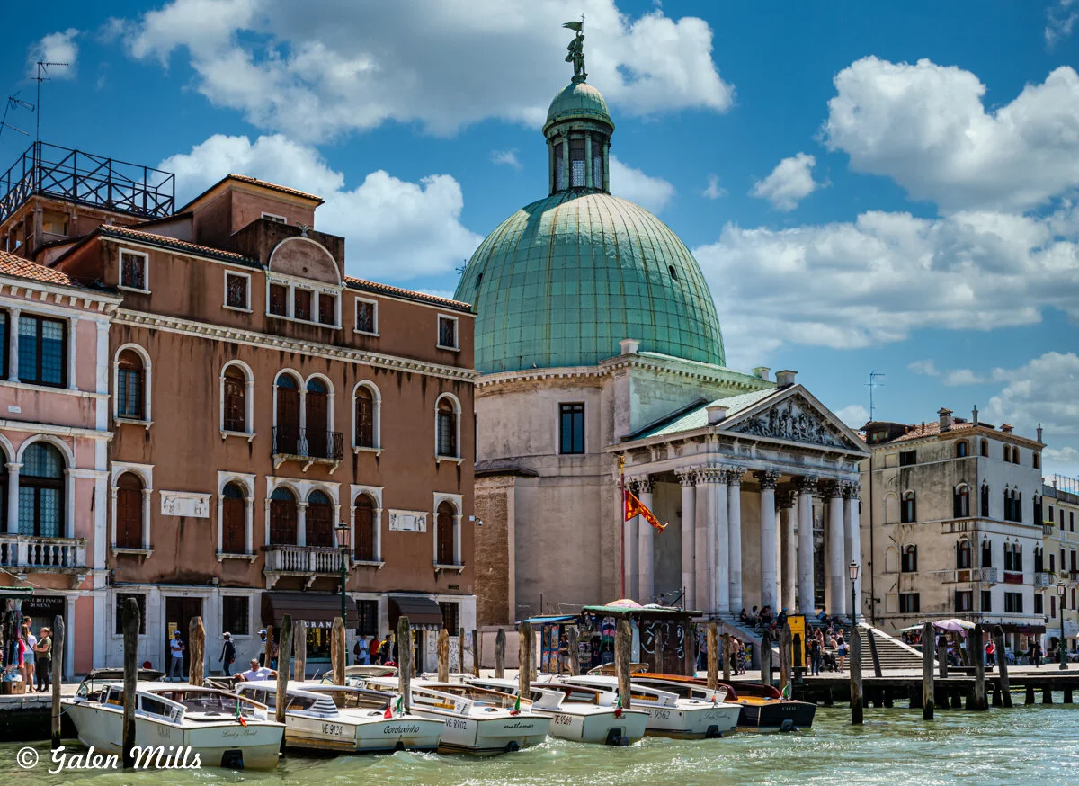 Venice canal with boats, historic buildings, and a dome in Italy.