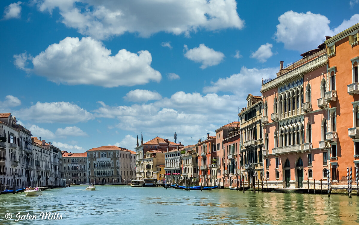 Venice Grand Canal with historic buildings and boats, under a partly cloudy sky.