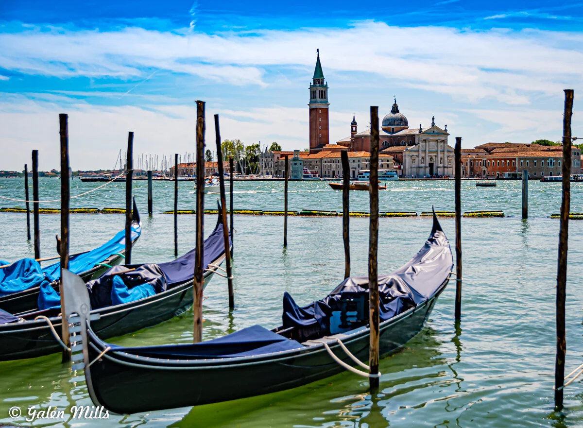 Venetian gondolas on water with a view of San Giorgio Maggiore Church in Venice.