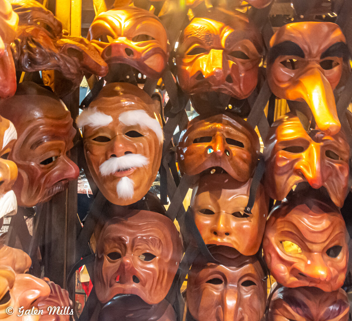 Collection of Venetian-style masks with various expressions and features, displayed on a rack.
