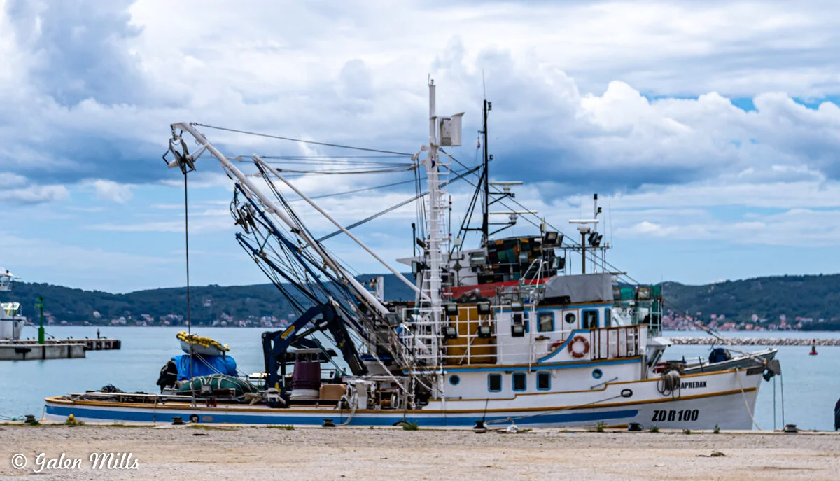Fishing boat docked on a calm sea with overcast skies