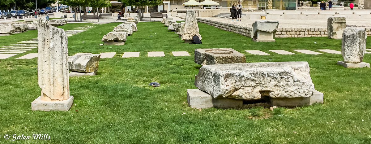 Ancient stone artifacts on grassy area with pathway
