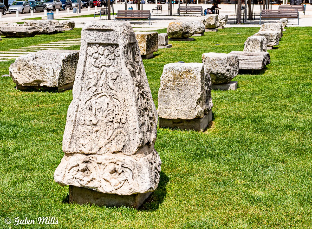 Ancient stone ruins with carvings on grass.