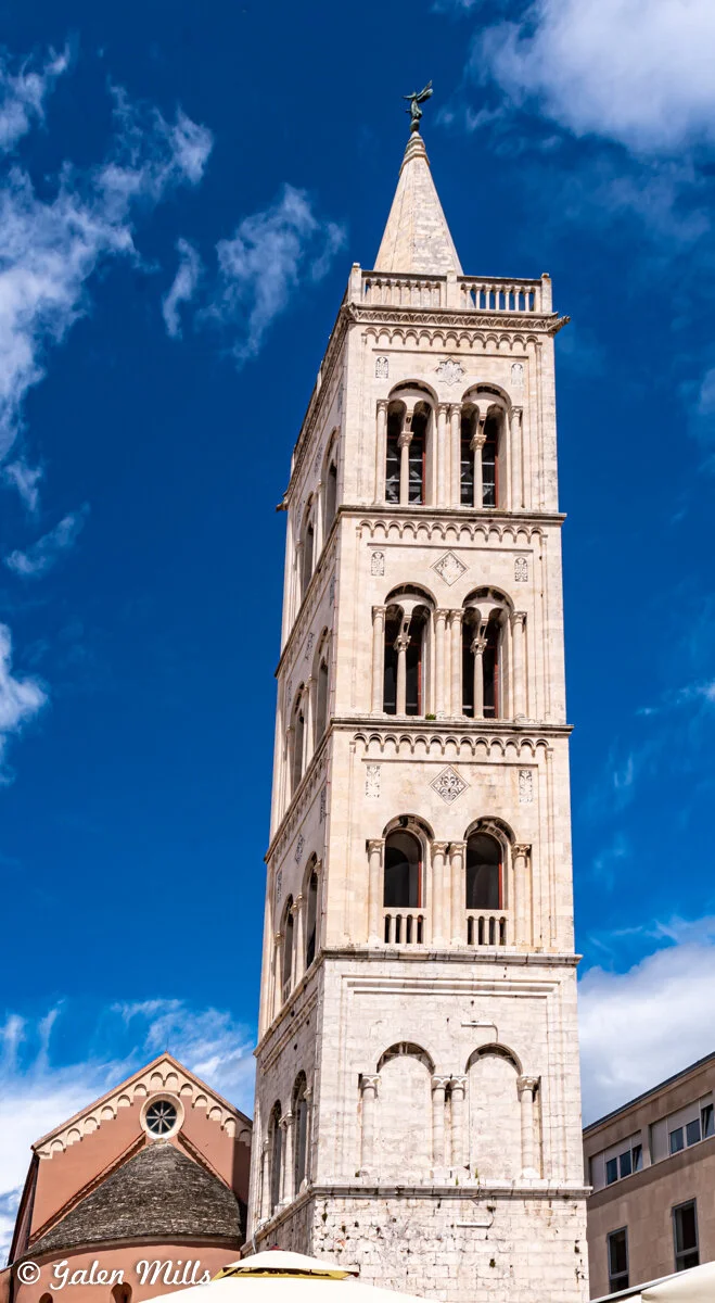 Historic bell tower under blue sky with clouds