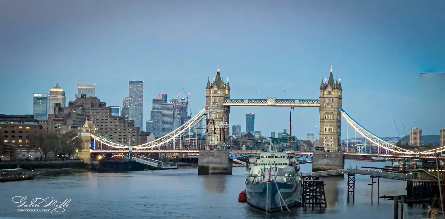 Tower Bridge in London with city skyline and river; evening view.