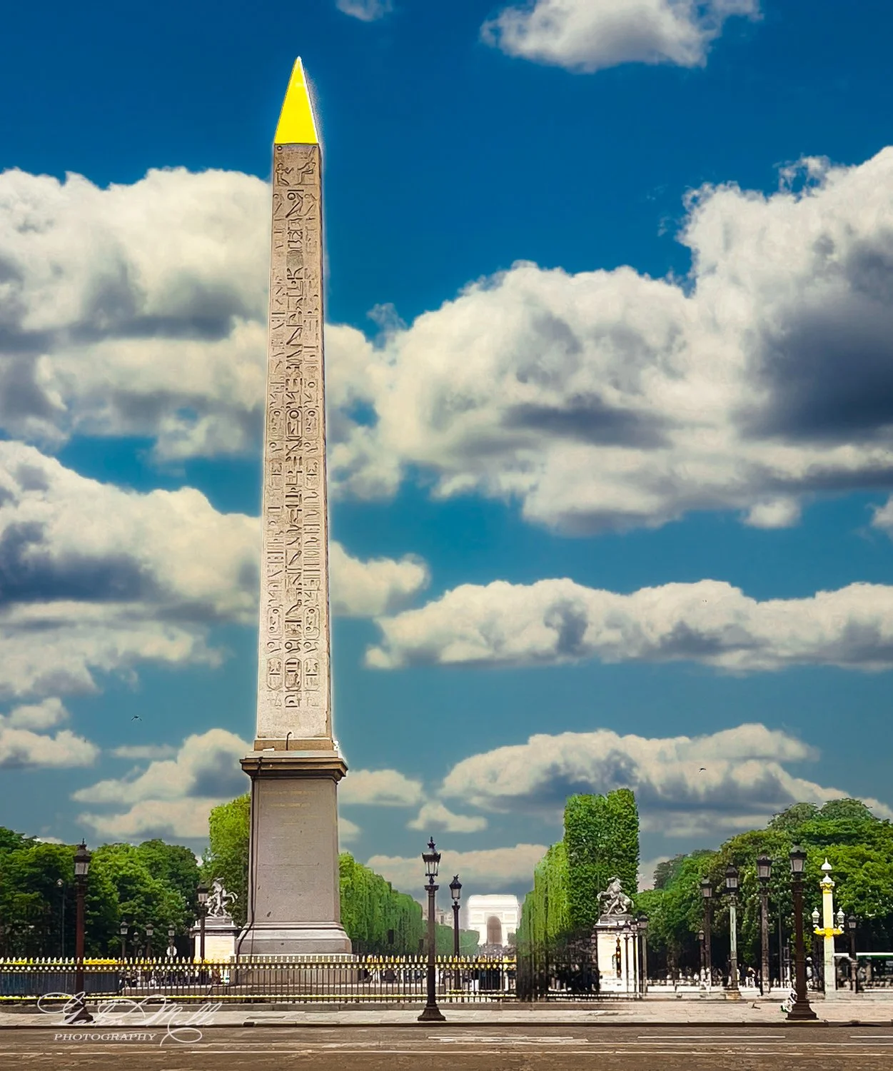 The Luxor Obelisk located in Place de la Concorde, Paris, with hieroglyphics engraved on its surface, set against a blue sky with clouds.