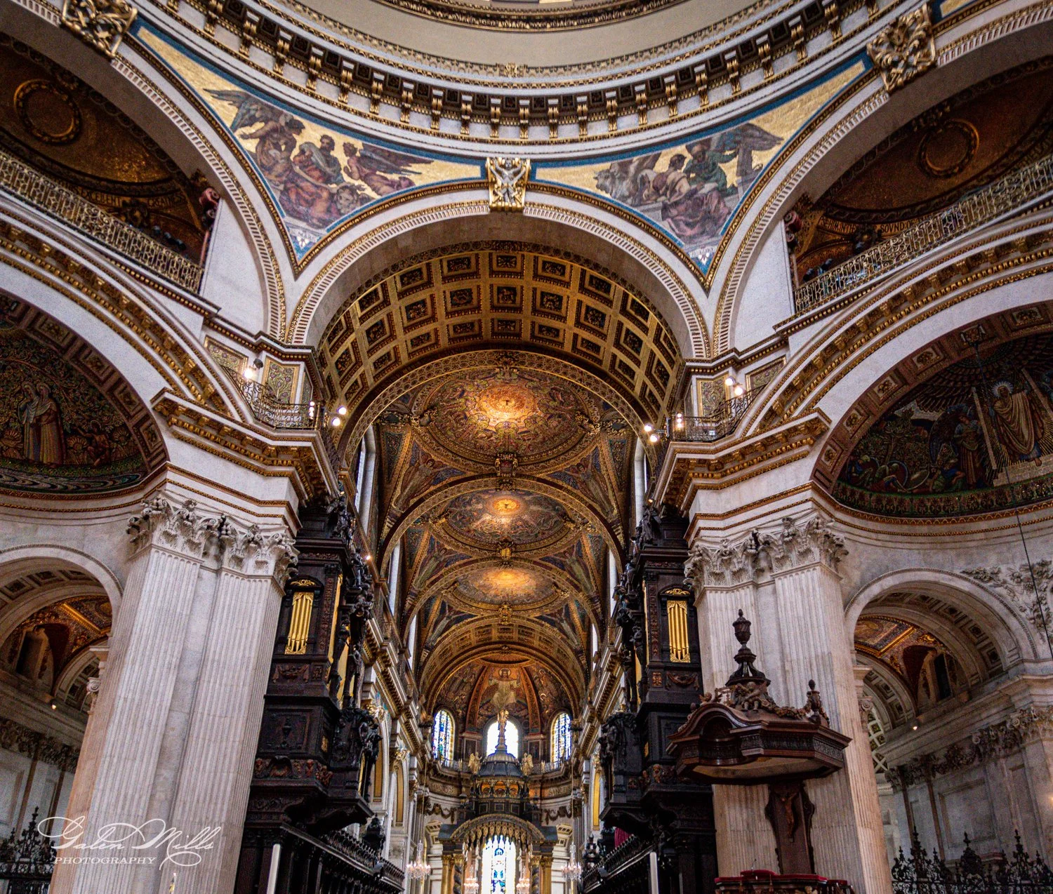 Interior of ornate cathedral with arches, columns, and detailed ceiling mosaics.