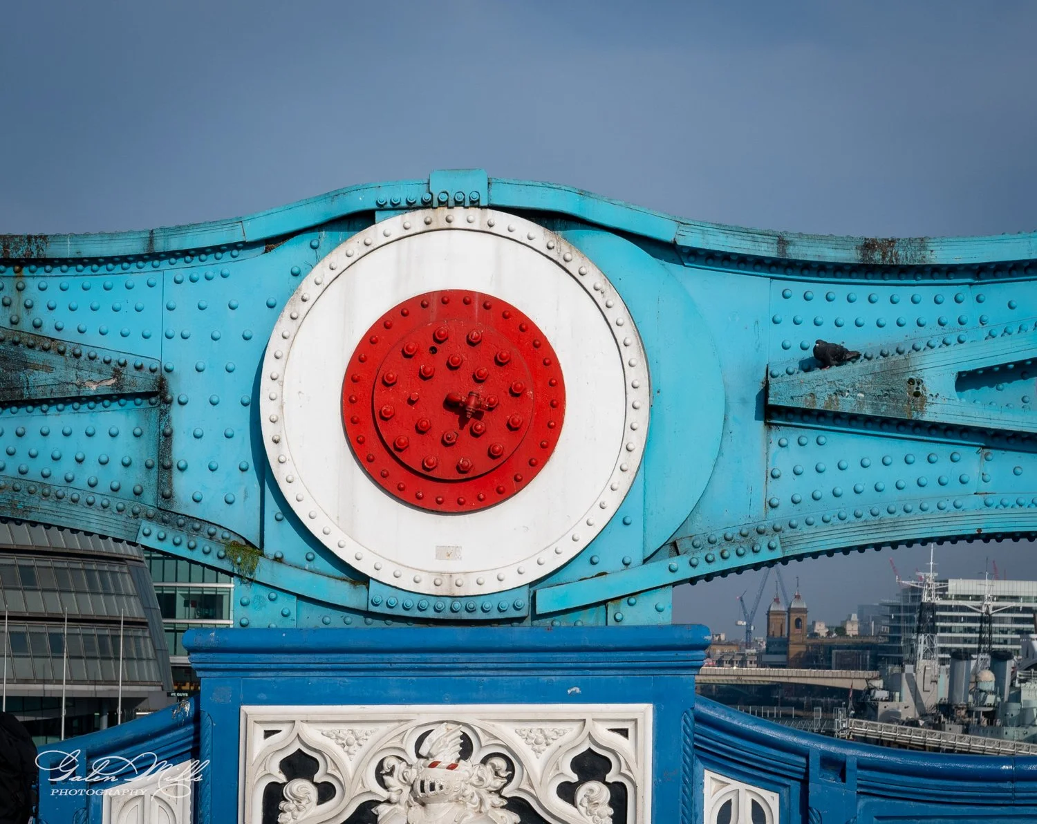 Close-up view of London Tower Bridge with central red and white circular design on blue metal structure.