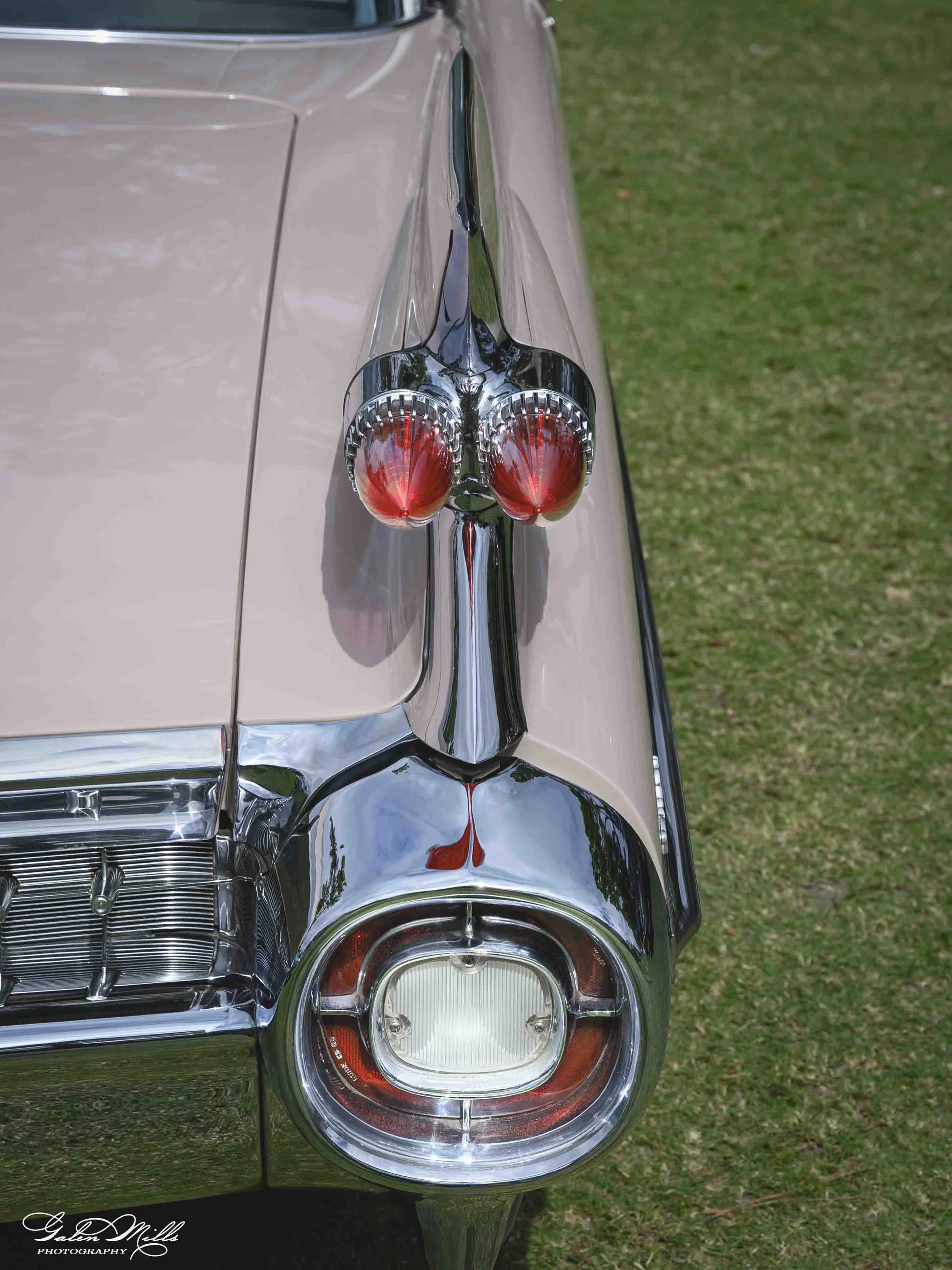 Close-up of the tail fin and tail light of a Cadillac, showing chrome details and a beige and brown paint job.
