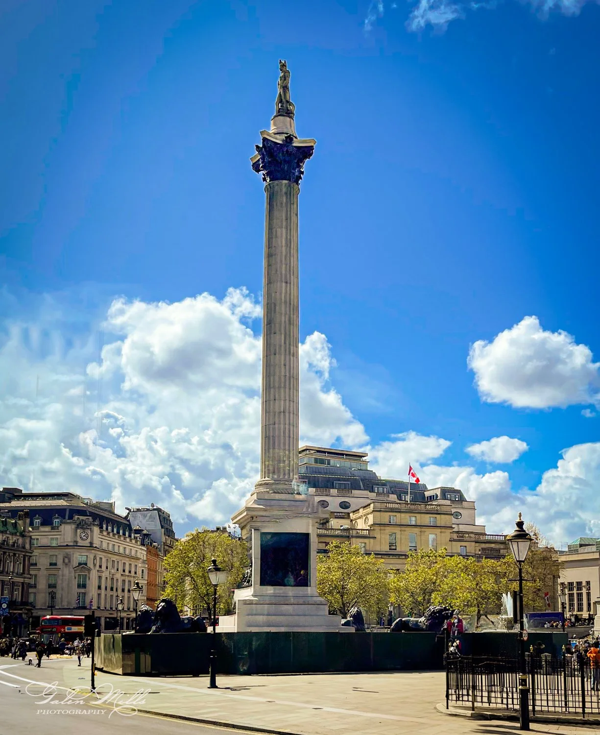 Nelson's Column in Trafalgar Square, London, with blue sky and clouds.