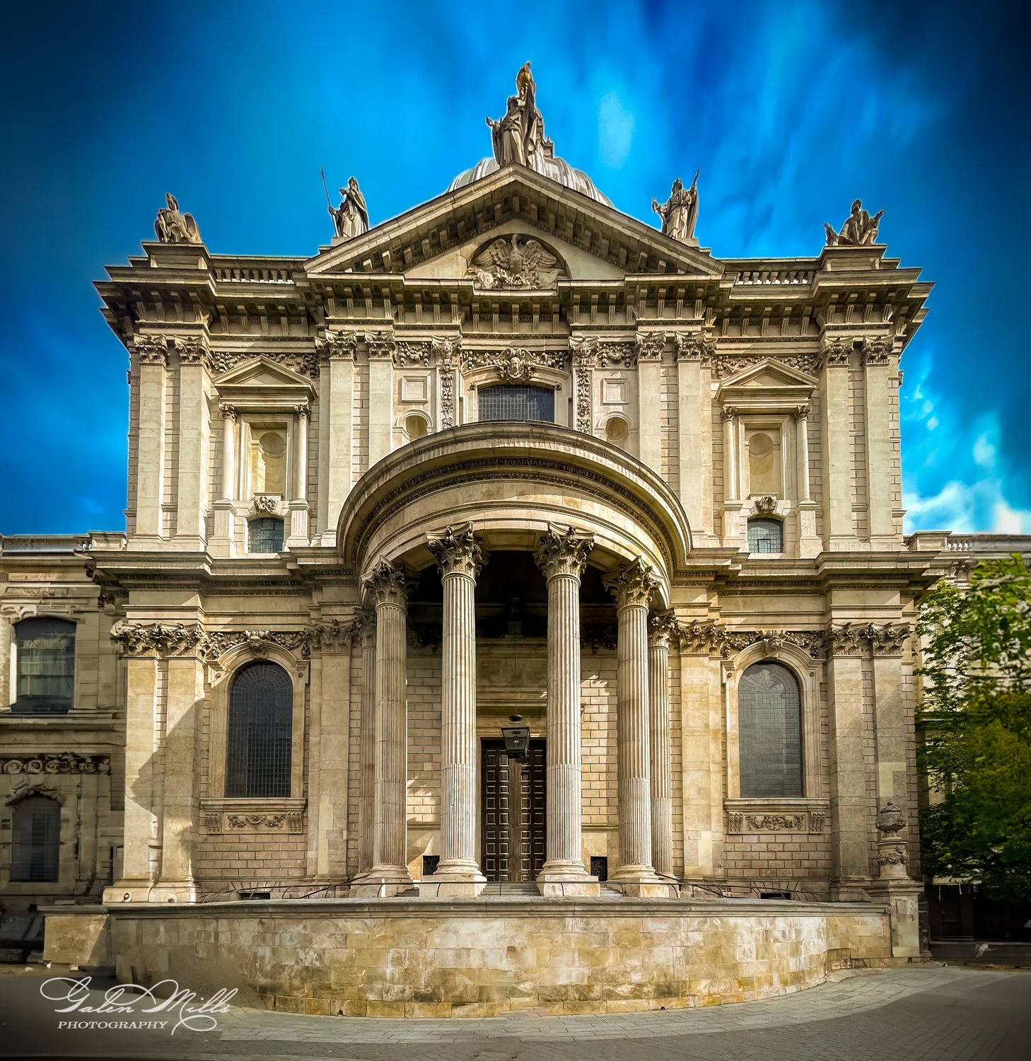 Historic building facade with columns and statues under a blue sky.