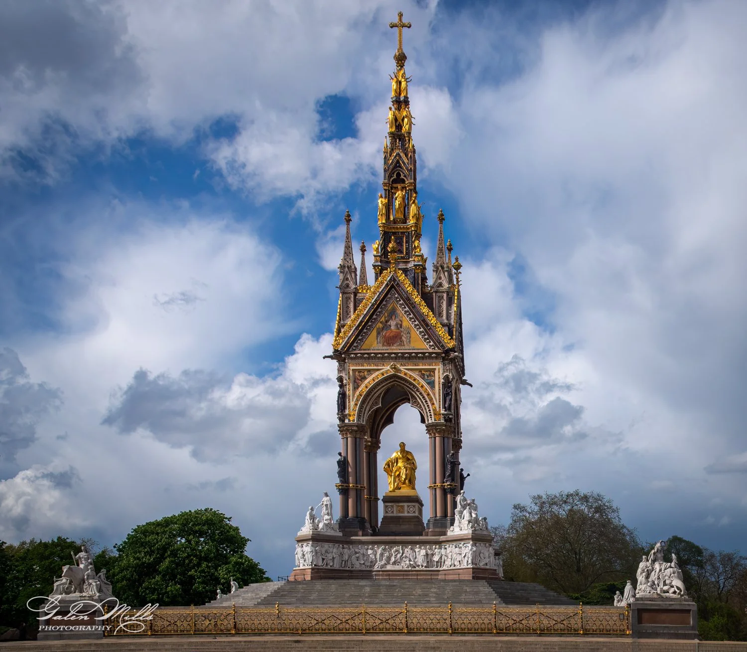 Albert Memorial with golden statue and ornate Gothic pinnacle against cloudy sky