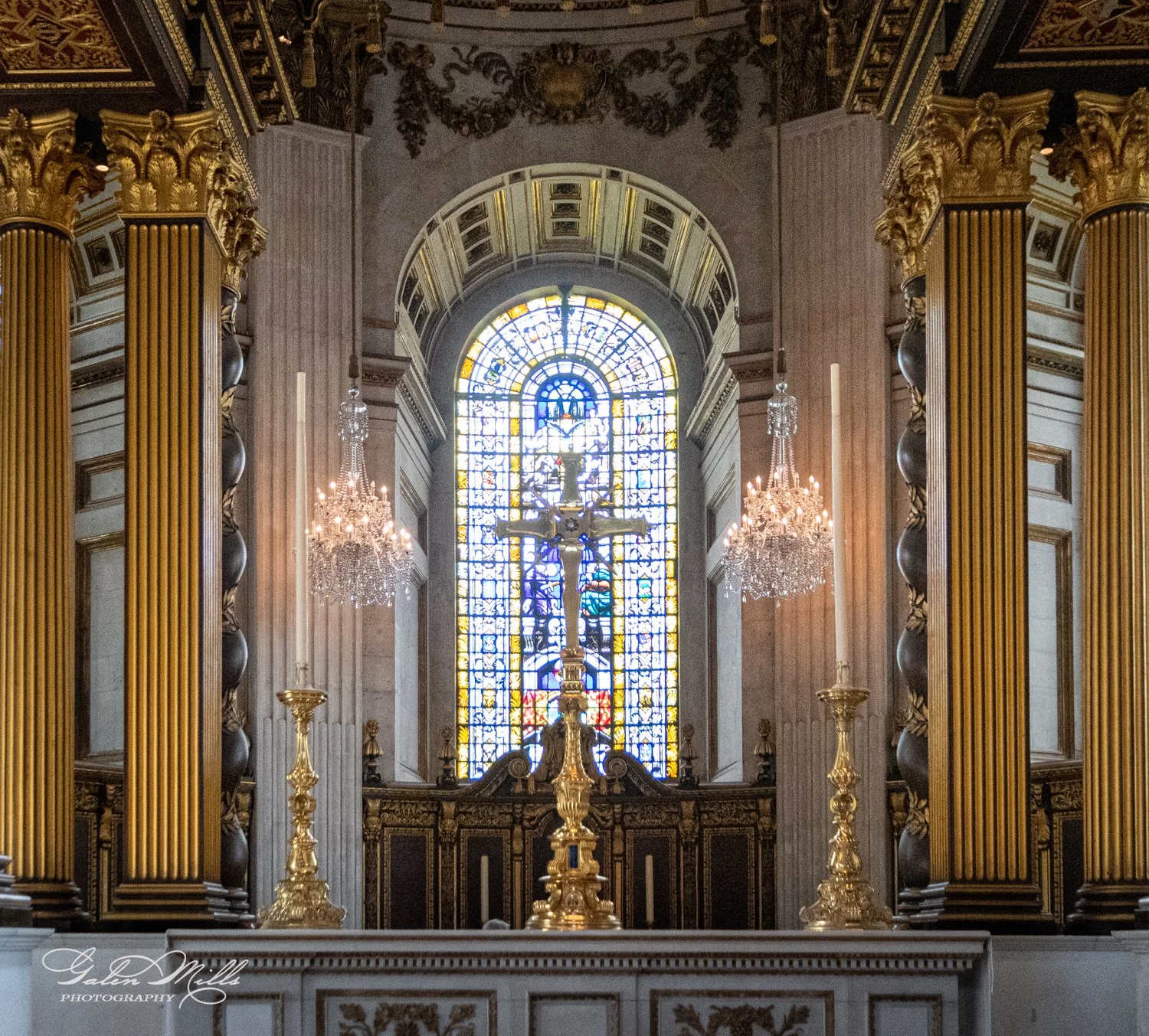 Interior of a church with ornate columns and a stained glass window