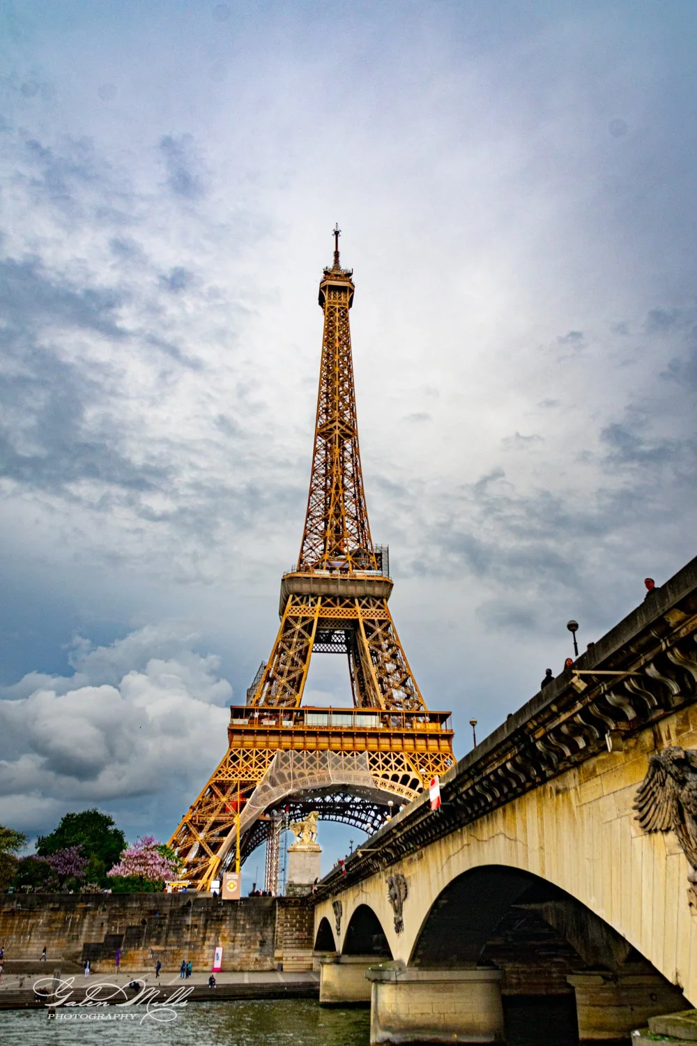 Eiffel Tower with cloudy sky and bridge in foreground, Paris, France.