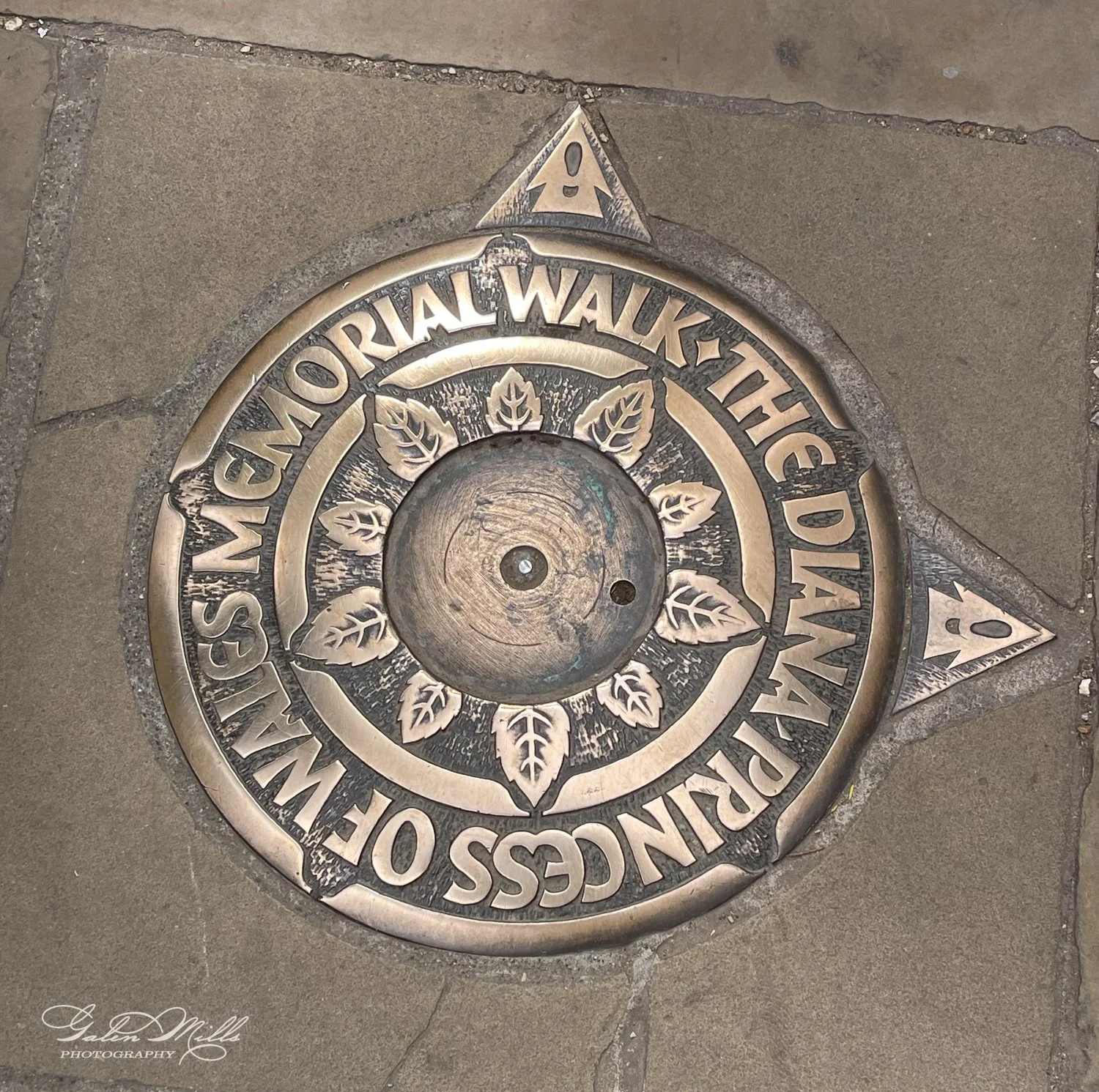 Bronze plaque on pavement marking The Diana Princess of Wales Memorial Walk, designed with leaf motifs.